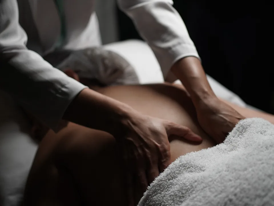 Sessão de massoterapia, mãos da terapeuta sobre as costas do colaborador